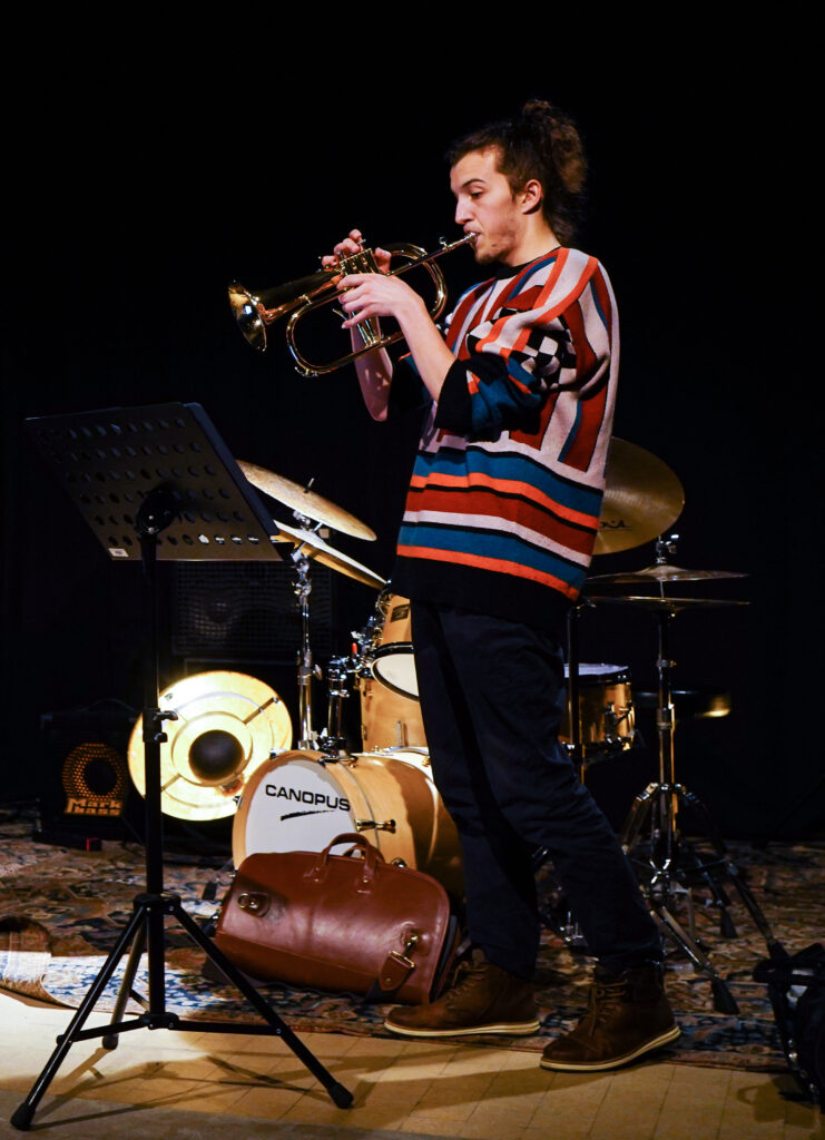 Media-Photo-12 Carlo Bechtel is performing on stage. He is soloing on his flugelhorn.